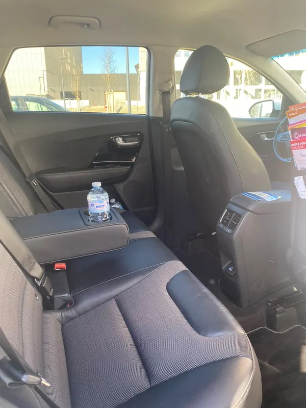Accoudoir central avec bouteille d’eau et brochures sur Toulouse dans le VTC de Louise